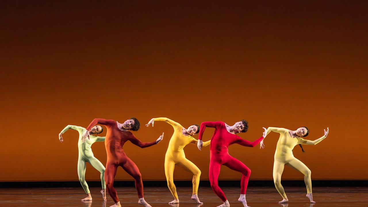 small group of modern dancers performing on a dark stage